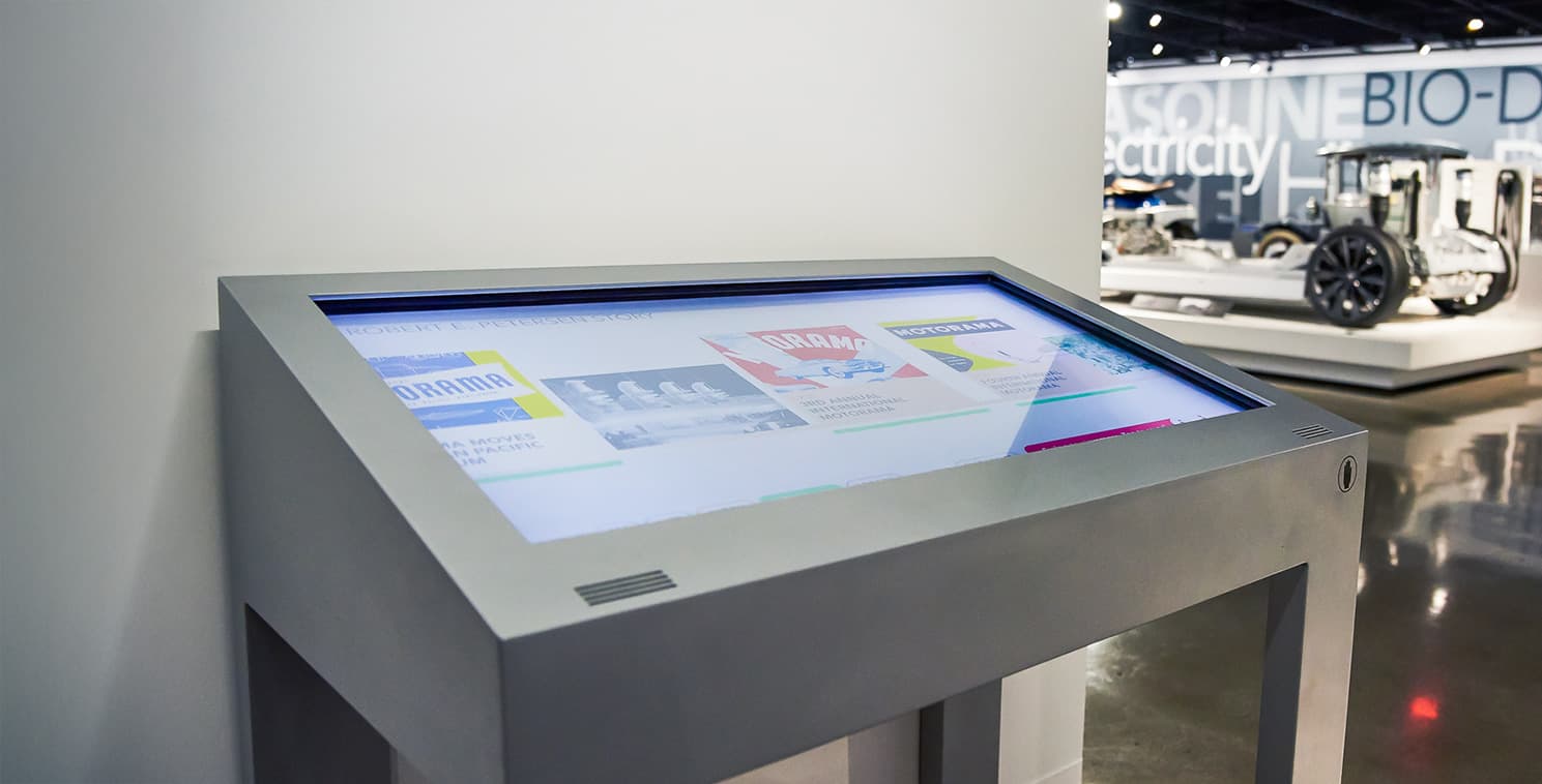 A large Elo open frame touchscreen at a museum or gallery displays digital exhibit content, enabling visitors to explore information through an interactive interface.
